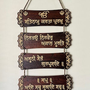 Puede incluir: Un colgante de pared de madera con cinco placas rectangulares de color marrón oscuro. Cada placa tiene texto dorado y bordes decorativos. Las placas están conectadas por una cadena marrón. El texto está en un idioma de escritura.