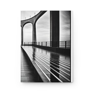 May include: A black and white photograph of a concrete bridge with a walkway leading to a view of the horizon. The walkway is wet from rain and reflects the sky and bridge.