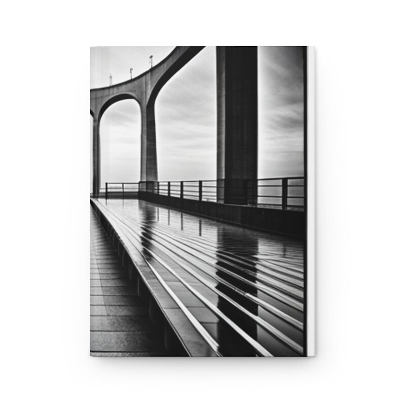 May include: A black and white photograph of a concrete bridge with a walkway leading to a view of the horizon. The walkway is wet from rain and reflects the sky and bridge.