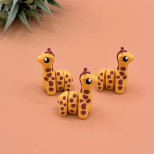 These 3D printed baby giraffe toys have black and white eyes, as well as brown spots.