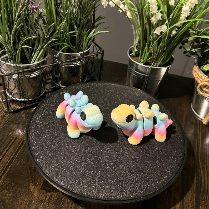 3D printed dinosaur toys are made with rainbow filament.