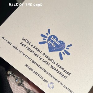 Puede incluir: El reverso de una tarjeta con el texto "BACK OF THE CARD" en la parte superior. La tarjeta tiene un logotipo azul en forma de coraz&oacute;n con las palabras "blue iris designs". La tarjeta tambi&eacute;n incluye el texto "WE'RE A SMALL BUSINESS DESIGNING AND PRINTING IN WEST YORKSHIRE!"