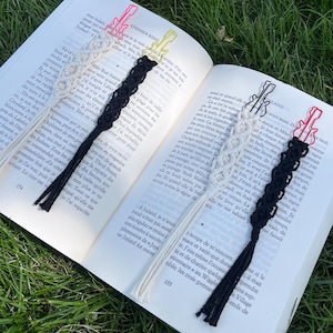 Peut inclure: Marque-pages en macramé en forme de guitare, roses, jaunes, noirs et crème, posés sur un livre ouvert. Le livre contient du texte de Stephen King. Les marque-pages ont une frange en bas.