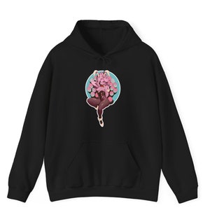 May include: Black hoodie with a graphic print of a pink and purple anime character with bunny ears. The character is sitting in a circle with a blue background and pink dots.
