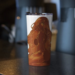 May include: A white stainless steel tumbler with a brown and orange illustration of a woman with long hair. The tumbler has a black lid.