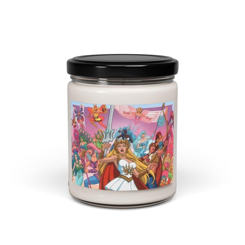 Puede incluir: Un tarro de vela blanco con una tapa negra y una imagen colorida de un grupo de personajes de dibujos animados, incluyendo una mujer con una espada y una corona, y un hombre con un arco y una flecha. Los personajes est&aacute;n rodeados de un fondo rosa y morado.