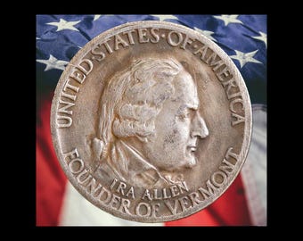 May include: A silver coin featuring a profile of a man with the text "UNITED STATES OF AMERICA" and "IRA ALLEN FOUNDER OF VERMONT". The coin is set against a backdrop of the American flag.
