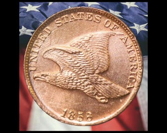 Peut inclure: Une pièce de monnaie couleur cuivre représentant un aigle en plein vol sur l'avers. Le texte UNITED STATES OF AMERICA est gravé le long du bord supérieur et l'année 1858 est inscrite en bas. La pièce est de forme circulaire et métallique.