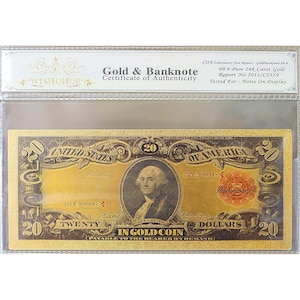 May include: A gold-colored twenty-dollar bill with a portrait of George Washington, encased in a protective sleeve. The bill is labeled "In Gold Coin" and "United States of America." The certificate of authenticity is visible at the top.