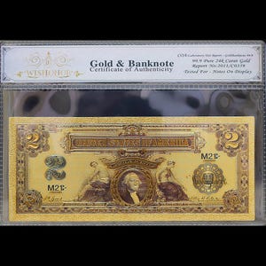 May include: A gold-plated two dollar bill from the United States of America. The bill features a portrait of George Washington and the text "Two Silver Dollars". The bill is encased in a clear plastic sleeve with a gold certificate of authenticity that reads "Gold & Banknote Certificate of Authenticity" and "99.9 Pure 24k Carat Gold".