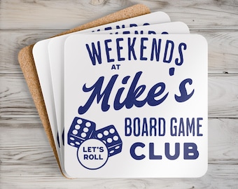 Peut inclure: Un ensemble de quatre sous-verres carrés aux coins arrondis, présentant une surface supérieure blanche avec un texte bleu foncé indiquant "WEEKENDS AT Mike's BOARD GAME CLUB" et "LET'S ROLL" dans un cercle, avec deux dés illustrés.
