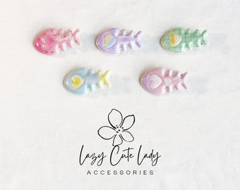 Puede incluir: Cinco accesorios en forma de espina de pescado en colores pastel. Cada accesorio presenta un color diferente: rosa, morado, verde, azul y rosa. Los accesorios tienen detalles de corazón y texto. Los accesorios son de Lazy Cute Lady Accessories.
