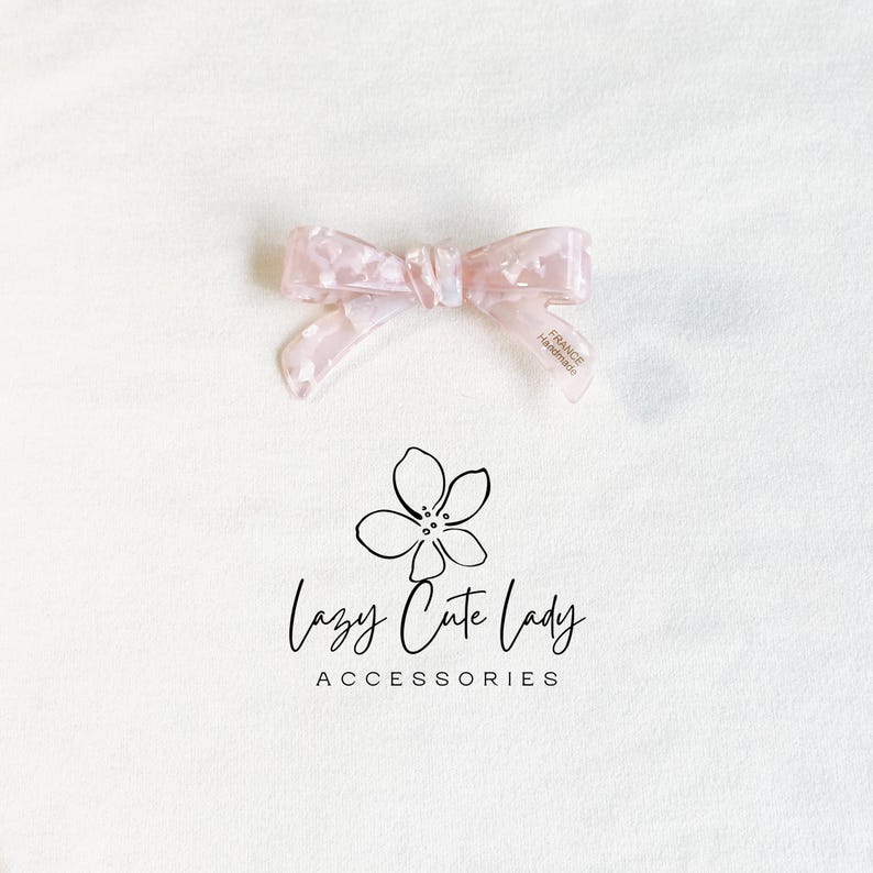 Pu&ograve; includere: Un fiocco rosa chiaro per capelli con un motivo marmorizzato. Il fiocco &egrave; realizzato in un materiale traslucido e presenta la scritta "FRANCE Handmade" su una delle code. Il logo "Lazy Cute Lady Accessories" &egrave; sotto il fiocco.