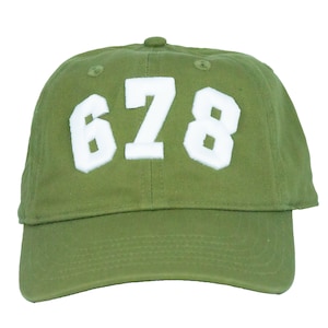 Könnte beinhalten: Eine grüne Baseballkappe mit weißen gestickten Zahlen "678" auf der Vorderseite.