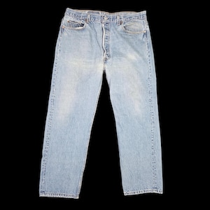 May include: Light blue denim jeans with a button fly and classic five-pocket design. The jeans have a faded wash and a straight leg fit. The image shows the jeans against a black background.