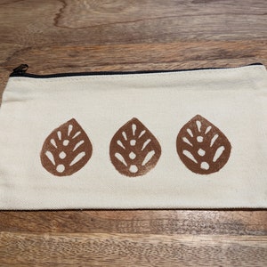 Sello de hoja marrón tallado a mano en una pequeña bolsa con cremallera.