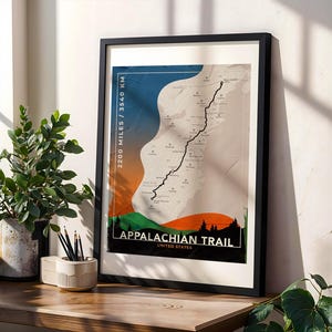May include: Framed print of the Appalachian Trail map, featuring a black line tracing the trail's path. The artwork includes text that reads "2200 Miles / 3540 KM" and "Appalachian Trail United States." The color palette includes blue, orange, green, and white.
