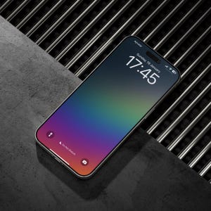 May include: A silver smartphone with a colorful gradient display. The screen shows the time as 17:45 on Sunday, January 19th. The phone is positioned on a dark, textured surface with a metal grate in the background.