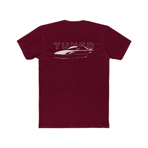 May include: A maroon t-shirt with a white outline of a car and the word "TUNED" printed on the back.