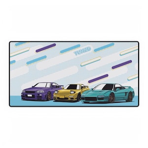 Könnte beinhalten: Eine blaue, gelbe und türkisfarbene Mausmatte mit weißem Hintergrund und dem Wort "TUNED" in Blau. Die Mausmatte zeigt drei Comic-Autos: einen lila Nissan Skyline GT-R, einen gelben Mazda RX-7 und einen türkisfarbenen Honda NSX.