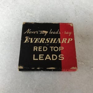 May include: A black and red box with the text "Never say leads - say EVERSHARP RED TOP LEADS" on it.