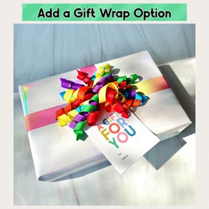 Op de afbeelding: Een witte cadeaudoos met een regenboog lint en een cadeaukaartje met de tekst "Een cadeau voor jou".