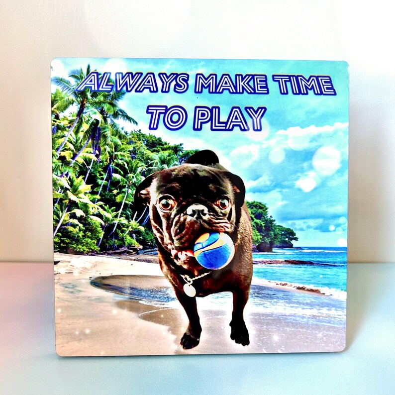 May include: A black pug dog with a blue ball in its mouth stands on a beach with palm trees and blue water in the background. The text "ALWAYS MAKE TIME TO PLAY" is written in blue and white letters at the top of the image.