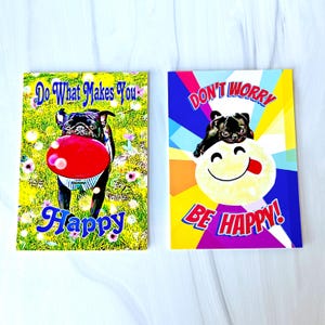 Puede incluir: Dos tarjetas de felicitaci&oacute;n coloridas con un perro pug en cada una. La primera tarjeta tiene un fondo amarillo, verde y azul con el texto "Haz lo que te haga feliz". La segunda tarjeta tiene un fondo morado, azul y amarillo con el texto "No te preocupes, s&eacute; feliz".
