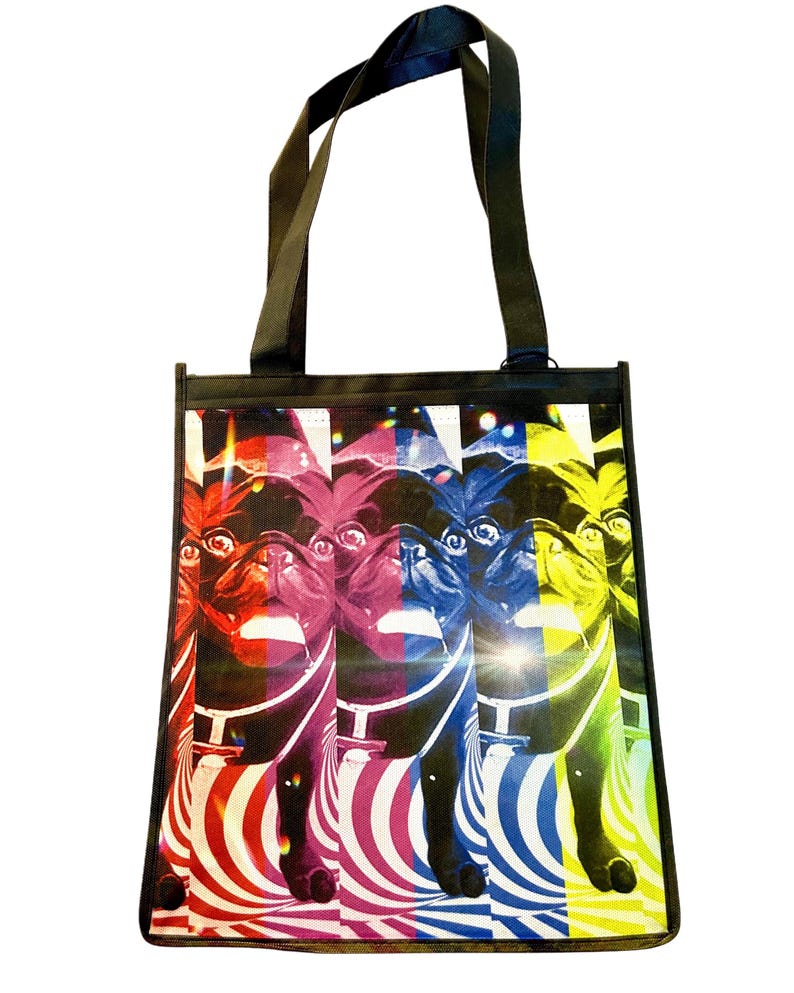 May include: A black tote bag with a colorful pop art design of a pug dog. The dog is depicted in four different colors: red, pink, blue, and yellow. The background is a swirling pattern of black and white stripes.