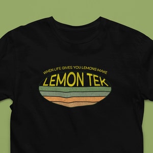 Puede incluir: Camiseta negra con un gráfico amarillo y verde que dice "When life gives you lemons make lemon tek".