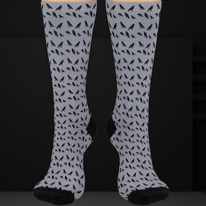 May include: A pair of gray socks with a black crow pattern. The socks are knee-high and have a black cuff.