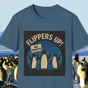 Könnte beinhalten: Ein blaues T-Shirt mit einem Grafikdruck von drei Pinguinen, die ein Schild mit der Aufschrift "Keine Zölle!" halten. Die Grafik ist im Retro-Stil mit einem blau-weißen Farbschema gehalten. Der Text "Flossen hoch!" ist in einem weißen Kreis um die Pinguine geschrieben.