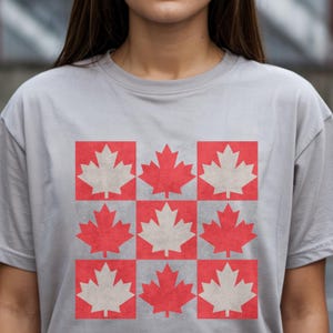 Puede incluir: Una camiseta gris con un diseño de nueve hojas de arce rojas y blancas dispuestas en una cuadrícula.
