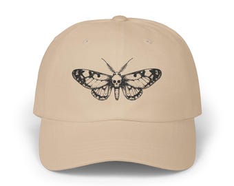 May include: A beige baseball cap with a black and white illustration of a moth with a skull head.