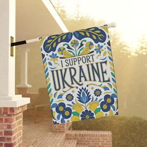 May include: A white garden flag with a blue and yellow floral pattern. The text "I Support Ukraine" is written in gold lettering.