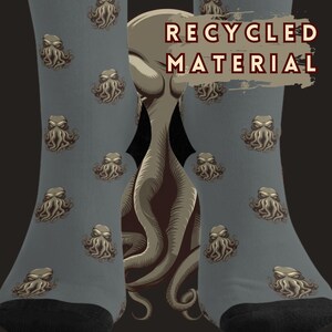 May include: A pair of gray socks with a repeating pattern of a brown octopus-like creature. The socks have black cuffs and the text "RECYCLED MATERIAL" is printed on the socks.