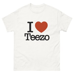 Op de afbeelding: Wit T-shirt met een zwarte afbeelding met de tekst "I love Teezo" met een rood hart.