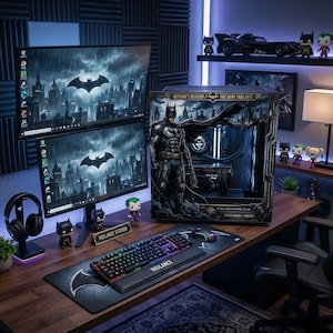 Könnte beinhalten: Ein Batman-Themen-Computer-Setup mit zwei Monitoren, die eine Stadtlandschaft und das Batman-Logo anzeigen. Der Schreibtisch umfasst eine Tastatur, eine Maus, ein Mauspad und Figuren. Ein Computergehäuse mit Batman-Artwork ist ebenfalls vorhanden, zusammen mit einem Headset und anderen dekorativen Gegenständen.
