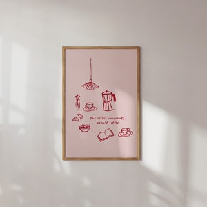 以下が含まれることがあります： ピンクの背景に、赤い線で描かれたコーヒーポット、コーヒーカップ、本、フルーツボウル、吊り下げ式の照明器具が描かれた額装されたプリント。テキスト「the little moments aren't little.」は赤で書かれています。