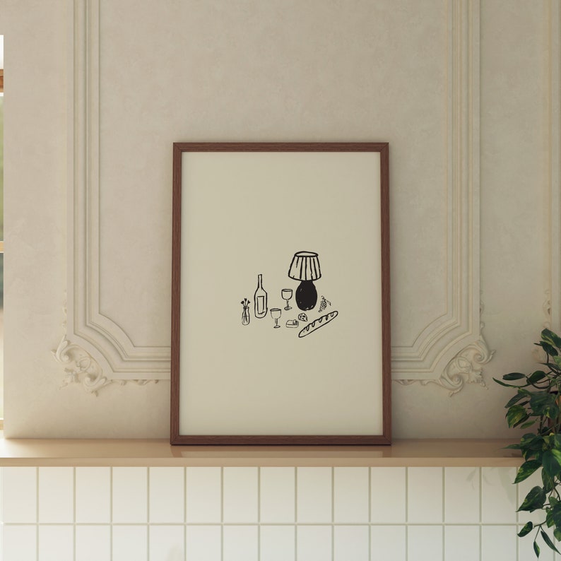 以下が含まれることがあります： 瓶、グラス、ランプ、バゲットが描かれた白黒の線画の静物画。絵は茶色の額縁に収められ、白い壁に掛けられている。