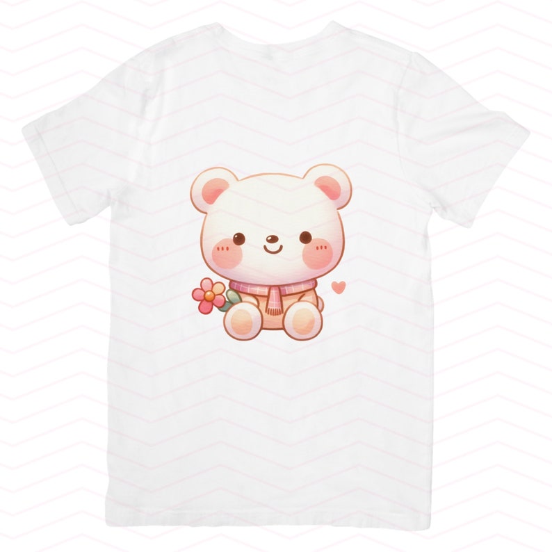 Op de afbeelding: Wit T-shirt met een cartoon afbeelding van een witte beer die een roze sjaal draagt en een roze bloem vasthoudt. De beer heeft roze wangen en een roze hart boven zijn hoofd.