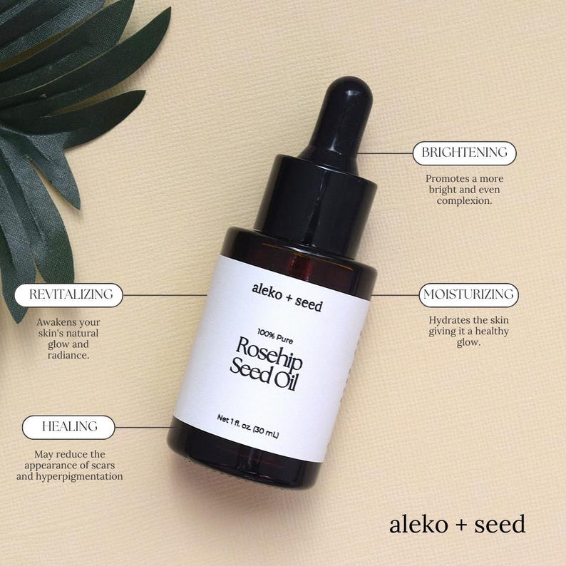 May include: A glass bottle of 100% pure rosehip seed oil with a black dropper top. The bottle is labeled "aleko + seed" and has a white label with the text "100% Pure Rosehip Seed Oil" and "Net 1 fl oz. (30 mL)". The bottle is sitting on a light brown surface. The image also includes text boxes with the words "Brightening", "Moisturizing", "Revitalizing", and "Healing" with descriptions of the benefits of the oil.
