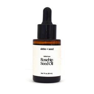 May include: A glass bottle with a black dropper top containing 100% pure rosehip seed oil. The bottle is labeled "aleko + seed" and "Net 1 fl oz. (30 ml)".