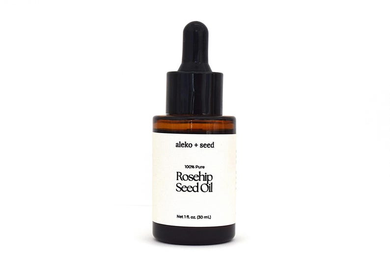 May include: A glass bottle with a black dropper top containing 100% pure rosehip seed oil. The bottle is labeled "aleko + seed" and "Net 1 fl oz. (30 ml)".
