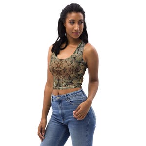 May include: A cropped tank top with a brown, green, and gold abstract print. The top has a scoop neck and a racerback style.