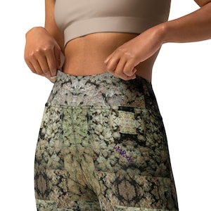 Könnte beinhalten: Hoher Bund Leggings mit einem abstrakten Muster in Grün, Braun und Weiß. Die Leggings haben ein lilafarbenes "We Rock" Logo am rechten Bein.