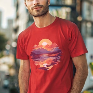 May include: Red t-shirt with a graphic print of a mountain landscape with a lake and a sunset. The graphic is in a circular shape and has a pixelated effect.