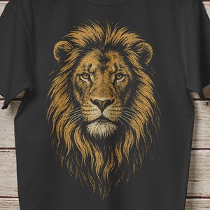 May include: Black t-shirt featuring a detailed illustration of a lion's head with a golden mane. The lion's face is centered, with a focused gaze. The design is printed on a black, short-sleeved tee shirt.