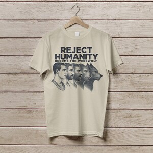 May include: A beige t-shirt featuring a graphic print of four men transforming into a werewolf. The text on the shirt reads "Reject Humanity Become the Werewolf".