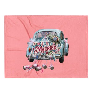 May include: A soft pink fleece blanket featuring a light blue vintage car decorated with flowers and ribbons. A sign on the back reads JUST MARRIED in colorful lettering. Several metal cans are tied to the rear bumper with ribbons.
